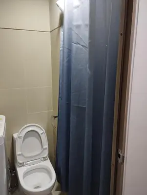 a bathroom with a toilet and a blue shower curtain at Sea Residences MOA by JO Alano New in Manila