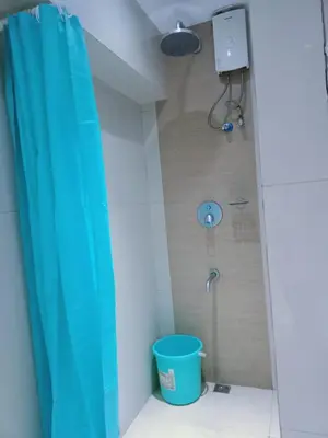 a bathroom with a blue shower curtain and a bucket at 2 Bedrooms Units Forbes Area 5th Avenue BGC Center in Manila