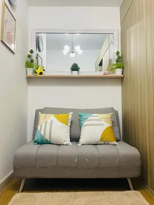 a gray couch with pillows on it in a room at Grace Residences 1 Bedroom With Balcony Bgc View Netflix in Manila