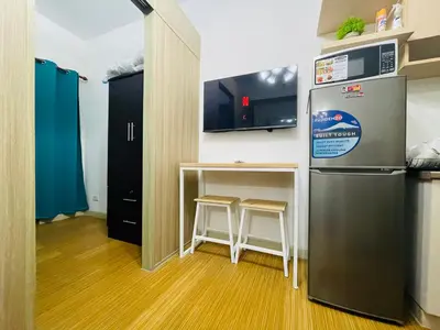 a kitchen with a refrigerator and a table with stools at Grace Residences 1 Bedroom With Balcony Bgc View Netflix in Manila