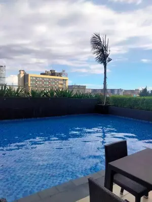 a swimming pool with a palm tree and a building at StayInMyCondo - 30th Condo in Pasay with Pool near Airport MOA,CCP & PICC In Pasay in Manila