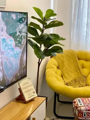 a yellow chair in a living room with a plant at 1BR Suite near Megamall, Boni & Shaw MRT Station in Manila