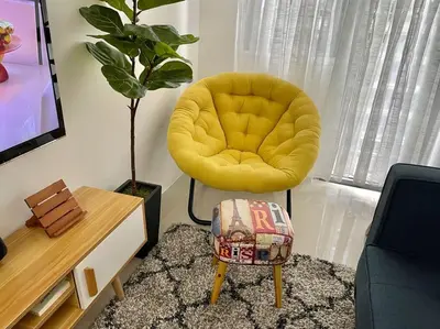 a living room with a yellow chair and a table at 1BR Suite near Megamall, Boni & Shaw MRT Station in Manila