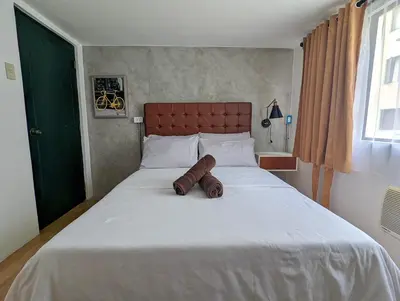 a bedroom with a large white bed with a brown headboard at Budget 1BR Loft Apartment in Cainta Cambridge Village in Cainta