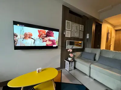 a living room with a couch and a tv on a wall at Beautiful 1bed condo Nr Airport, MOA, Makati, Bay in Manila