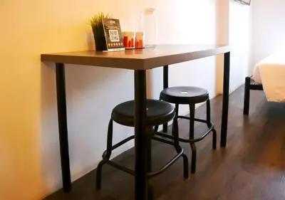 a wooden table with two stools in a room at mySTAY Hotel BGC East in Manila