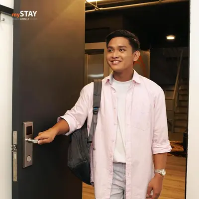 a young boy is opening the door to a elevator at mySTAY Hotel BGC East in Manila