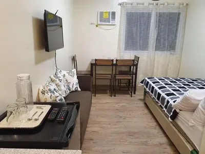 a living room with a bed and a tv and a couch at Lilian Stanford Suites 2 South Forbes Inchican Silang Cavite in Silang