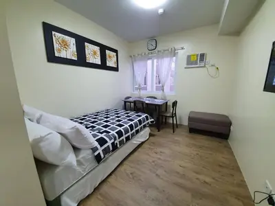 a bedroom with a bed and a table in it at Lilian Stanford Suites 2 South Forbes Inchican Silang Cavite in Silang