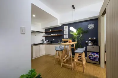 a kitchen with a table and stools in a room at Bella Vita at Grace Residences in Manila