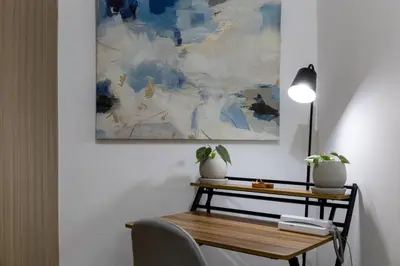 a desk with a lamp and a painting on the wall at Bella Vita at Grace Residences in Manila