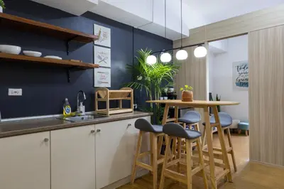 a kitchen with a table and stools in a room at Bella Vita at Grace Residences in Manila