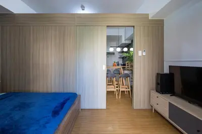 a bedroom with a bed and a television and a kitchen at Bella Vita at Grace Residences in Manila