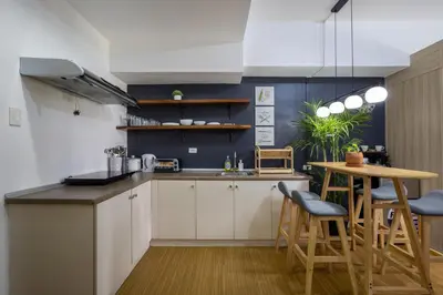 a kitchen with white cabinets and a table and chairs at Bella Vita at Grace Residences in Manila
