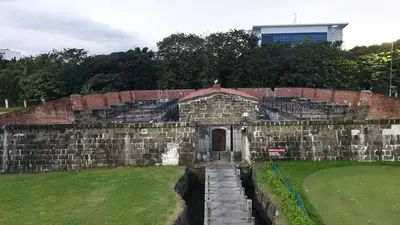 an old brick building with a gate in a field at USA embassy front suite Pearl of the Orient in Manila