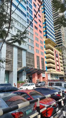 a parking lot with cars parked in front of tall buildings at USA embassy front suite Pearl of the Orient in Manila