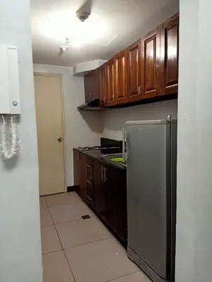 a kitchen with wooden cabinets and a stainless steel refrigerator at Taj's Condotel in Manila