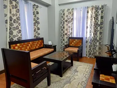 a living room with two chairs and a table at Taj's Condotel in Manila