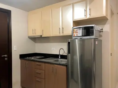 a kitchen with a stainless steel refrigerator with a microwave on top at Hotel Type Condo Near NAIA Manila Airport in Manila