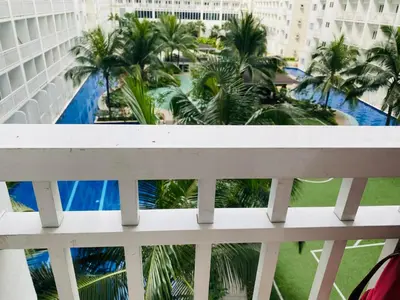 a balcony with a view of a pool and palm trees at Shore Residence D1,shortwalk MALL OF ASIA near airport wifi in Manila