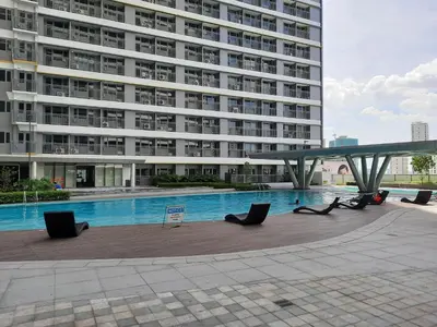 a large building with a swimming pool in front of a building at SMDC FAME Residences David 's place in Manila