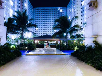 a large building with palm trees in front of it at Sabina's one bedroom condo at Shore tower C in Manila