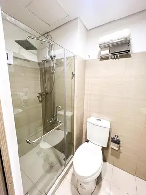a bathroom with a toilet and a glass shower at Sabina's one bedroom condo at Shore tower C in Manila