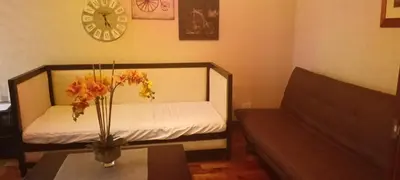 a small room with a table with a vase of flowers at 18F staycation in Manila