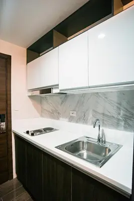a kitchen with white cabinets and a stainless steel sink at Serene Escape at Air Residences 2160 Makati in Manila