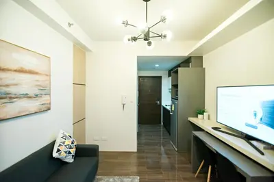 a living room with a black couch and a large screen at Serene Escape at Air Residences 2160 Makati in Manila