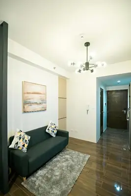 a living room with a black couch and a ceiling at Serene Escape at Air Residences 2160 Makati in Manila