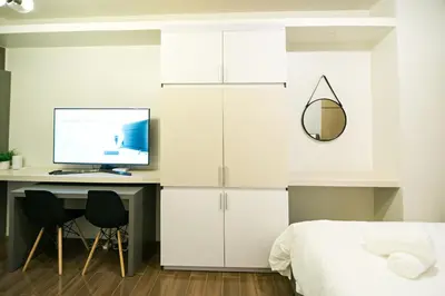 a bedroom with a bed and a desk with a computer at Serene Escape at Air Residences 2160 Makati in Manila