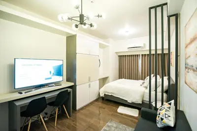 a bedroom with a bed and a desk with a television at Serene Escape at Air Residences 2160 Makati in Manila