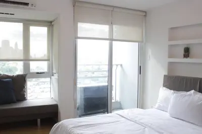 a bedroom with a white bed and a window at A2J Luxury 1BR BGC Balcony Suite Near BurgosCircle in Manila