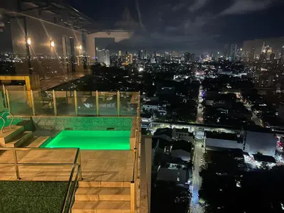 a building with a pool on the roof at night at Spacious One Bedroom 20888 in Manila