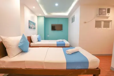 two beds in a room with blue and white at Arzo Hotel Premier in Manila