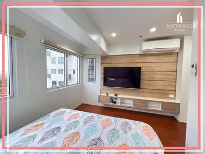 a bedroom with a bed and a flat screen tv at Panoramic View of City 1BR Loft Unit FREE WIFI & NETFLIX at Fort Victoria BGC in Manila