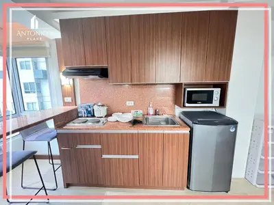a kitchen with wooden cabinets and a sink and a microwave at Panoramic View of City 1BR Loft Unit FREE WIFI & NETFLIX at Fort Victoria BGC in Manila
