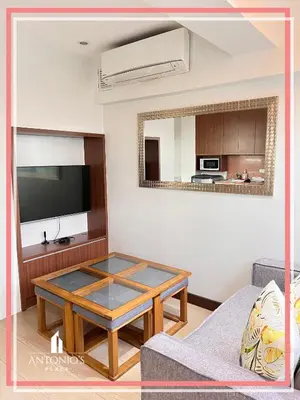 a living room with a coffee table and a tv at Panoramic View of City 1BR Loft Unit FREE WIFI & NETFLIX at Fort Victoria BGC in Manila