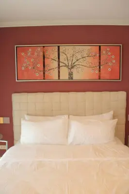 a bedroom with a white bed with three paintings above it at A2J BGC Luxury 1BR Suite Near Burgos Circle & Mall in Manila