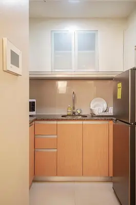 a kitchen with white cabinets and a stainless steel refrigerator at Cozy and Classy Studio Across Airport Terminal 3 in Manila
