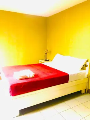 a yellow bedroom with a bed with a red blanket at Benson Hotel San Juan CIty in Manila