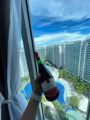 a person holding a bottle of wine looking out of a window at S-A-F-E Haven Resort Staycation in Manila