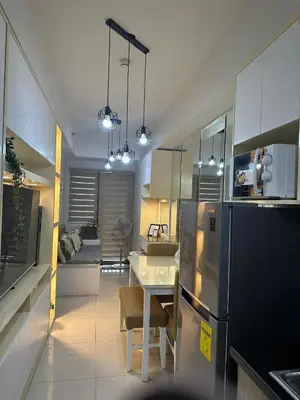 a kitchen with a table and a refrigerator at Mel and Rose Place in S Residences Tower 1 MOA in Manila