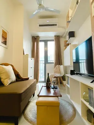 a living room with a couch and a flat screen tv at Fame Residences Tower-1 Unit 3207 in Mandaluyong 1 Br w Balcony City view in Manila
