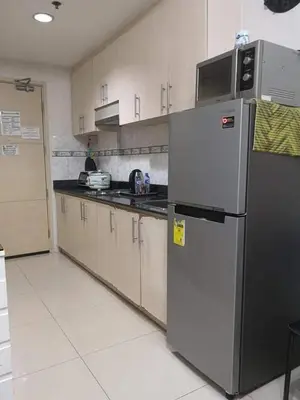 a kitchen with a stainless steel refrigerator and cabinets at Sea Residences Prestige in Manila