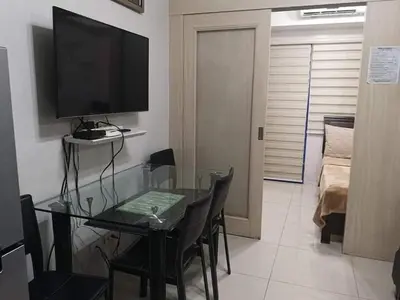 a living room with a glass table and a television at Sea Residences Prestige in Manila