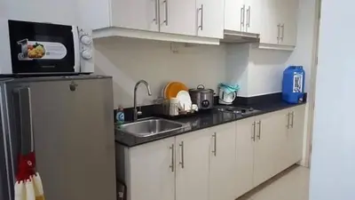 a kitchen with white cabinets and a sink and a microwave at Easy Stay Sea Residences in Manila