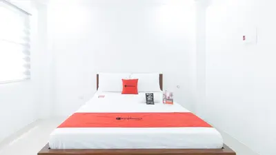 a white bedroom with a bed with a red pillow at RedDoorz Plus at DBuilders Poblacion BGC in Manila