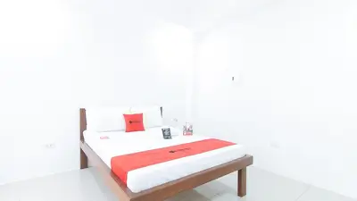 a white bedroom with a bed with red and white sheets at RedDoorz Plus at DBuilders Poblacion BGC in Manila